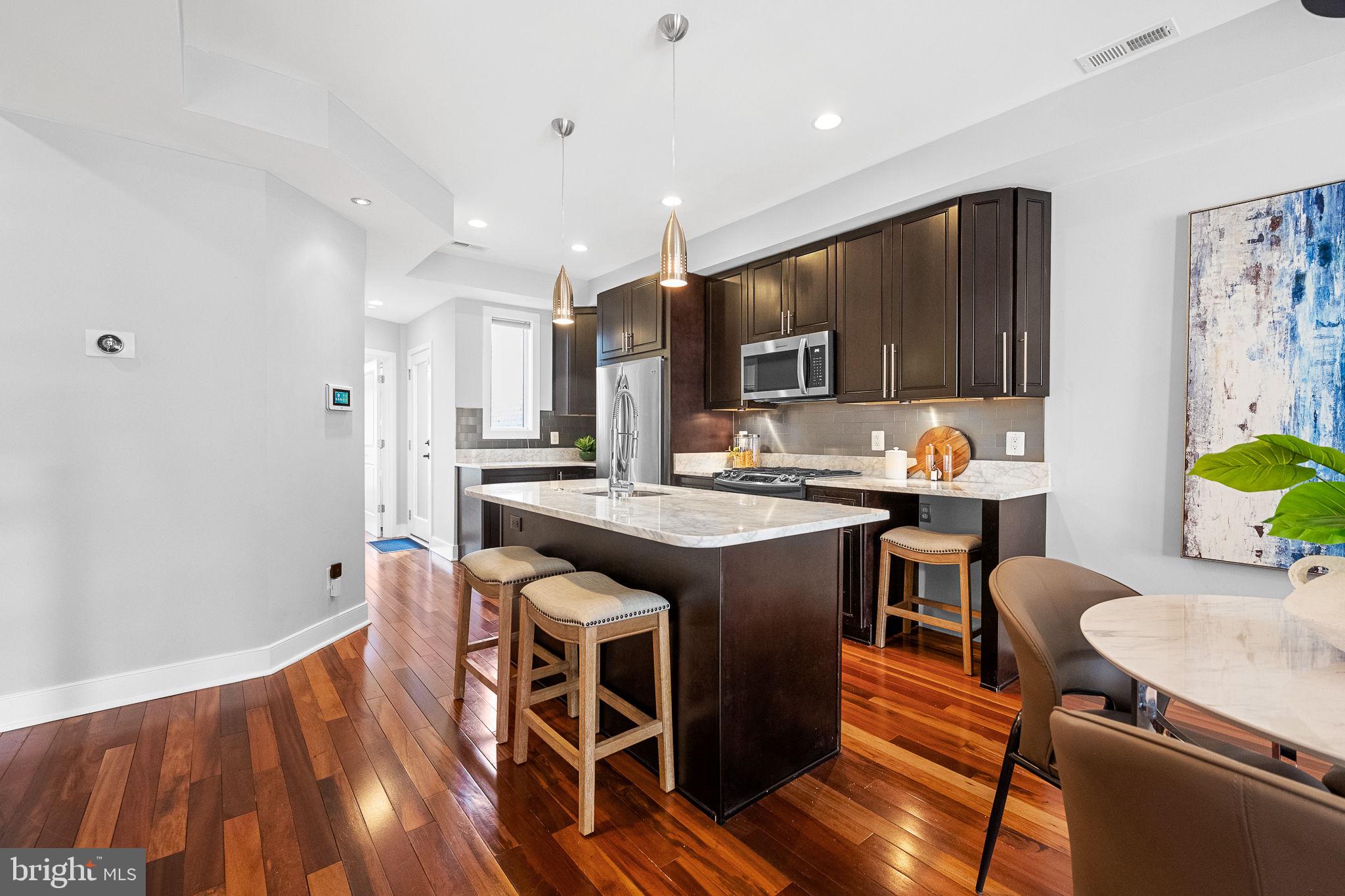 2819 11th Street Northwest, Unit 2 Washington, DC 20001 - Photo 11 of 36 a kitchen with stainless steel appliances granite countertop a stove top oven a dining table and chairs with wooden floor