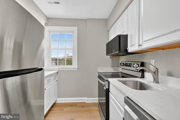 a kitchen with stainless steel appliances a sink a microwave a refrigerator and cabinets