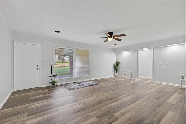 a view of empty room with wooden floor and fan