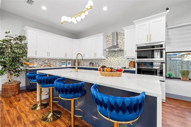 a kitchen with stainless steel appliances granite countertop a sink dishwasher a microwave oven a stove a dining table and chairs with wooden floor