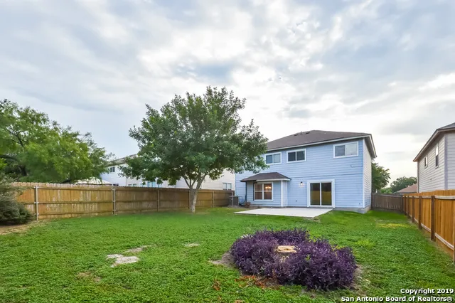 a view of a house with a big yard potted plants and large tree
