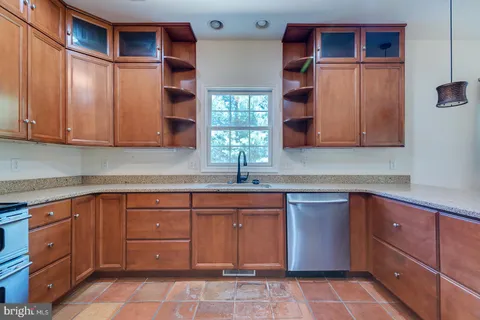 a large kitchen with granite countertop a large kitchen island a sink stainless steel appliances and cabinets