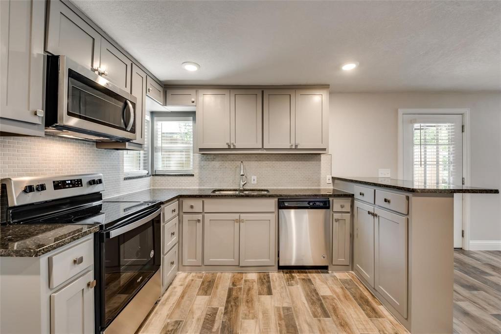 a kitchen with stainless steel appliances white cabinets granite counter tops a stove a sink and dishwasher
