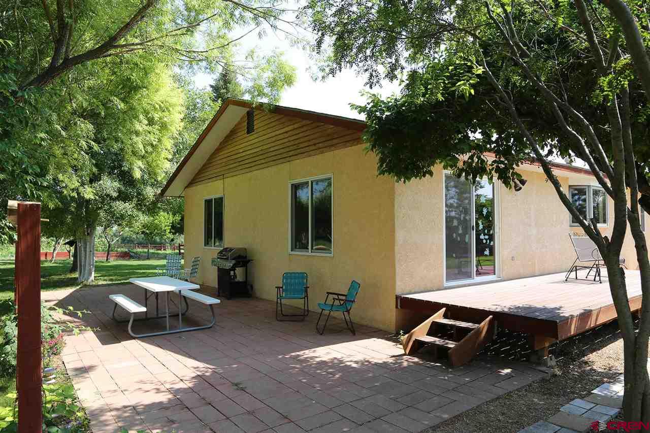 3946 1550 Road Delta, CO 81416 - Photo 27 of 35 a view of a backyard with table and chairs and a barbeque with potted plants and large trees