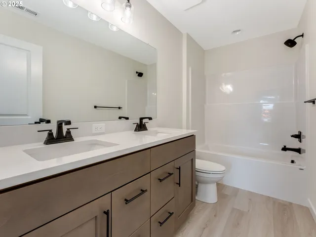 a bathroom with a double vanity sink toilet a shower and a bathtub