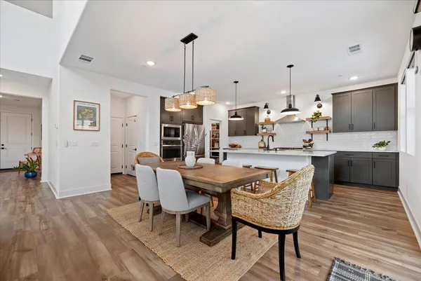 a view of a kitchen with kitchen island stainless steel appliances refrigerator a table and chairs