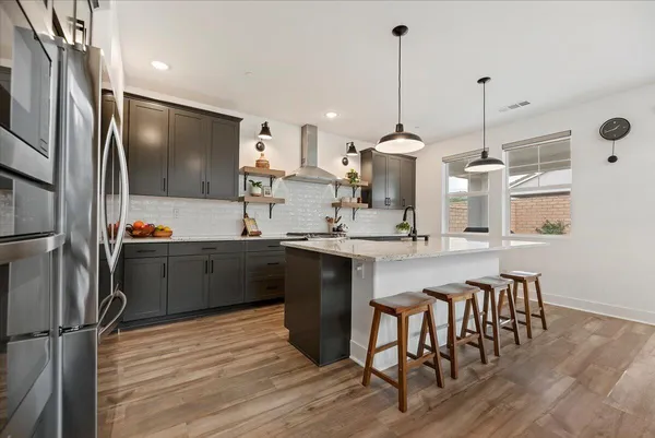 a kitchen with stainless steel appliances kitchen island granite countertop a sink refrigerator and cabinets