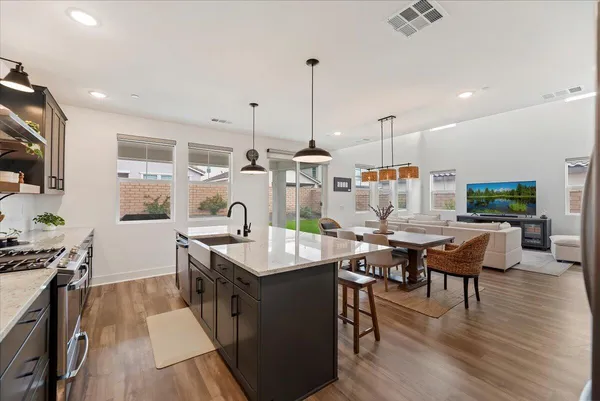 a kitchen with stainless steel appliances granite countertop a stove top oven a sink dishwasher and white cabinets with wooden floor