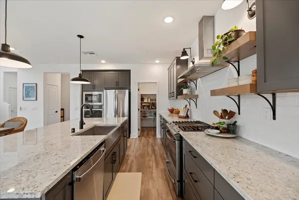 a kitchen with stainless steel appliances granite countertop a sink a stove and a wooden floors