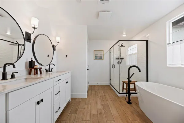 a bathroom with a double vanity sink mirror and bathtub
