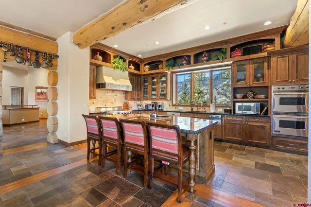 a dining hall with stainless steel appliances granite countertop a stove a refrigerator a dining table and chairs with wooden floor