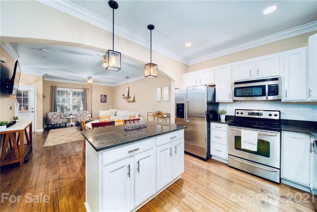 a kitchen with stainless steel appliances kitchen island granite countertop a stove a sink and a refrigerator