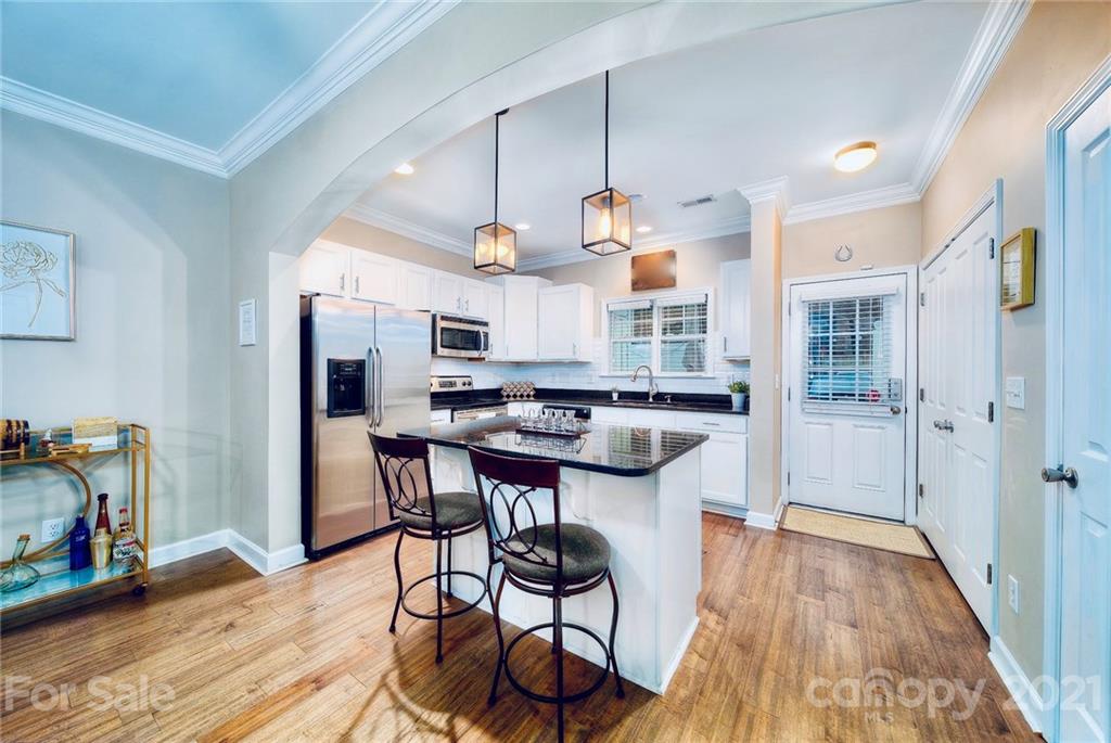 4142 Walker Road Charlotte, NC 28211 - Photo 3 of 18 a kitchen with stainless steel appliances a dining table chairs stove and cabinets