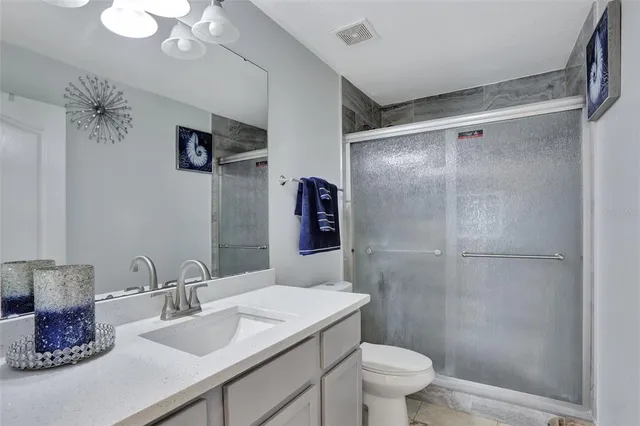 a bathroom with a granite countertop sink a toilet a shower and a mirror