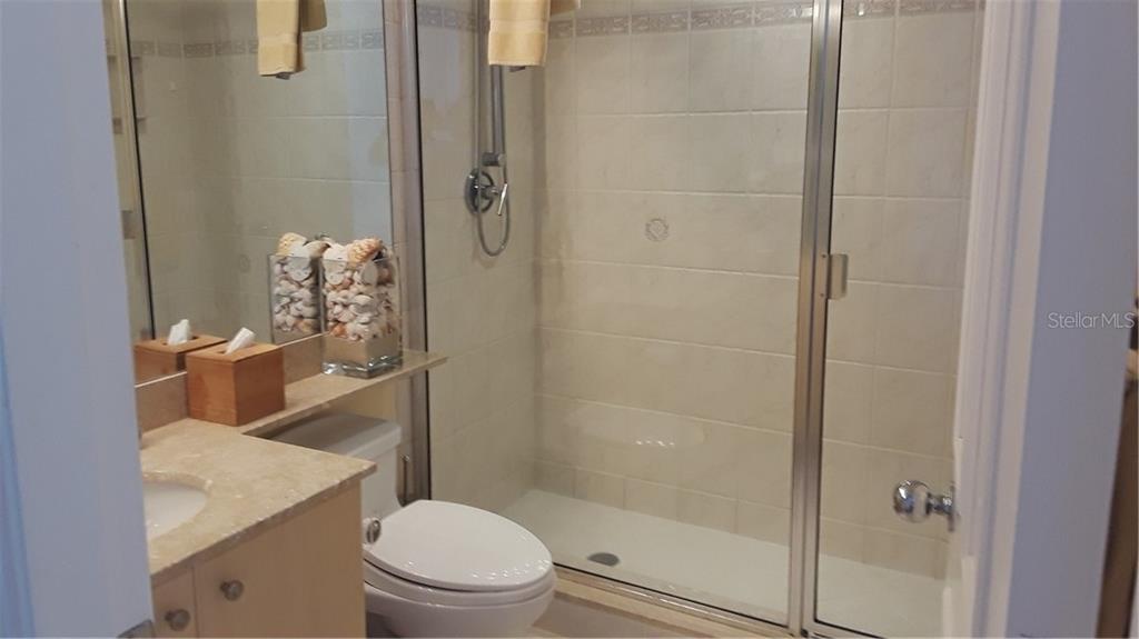455 Longboat Club Road, Unit 401 Longboat Key, FL 34228 - Photo 21 of 28 a bathroom with a granite countertop toilet a sink and shower