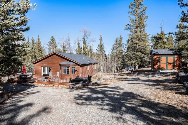 a view of house with outdoor seating and trees in the background