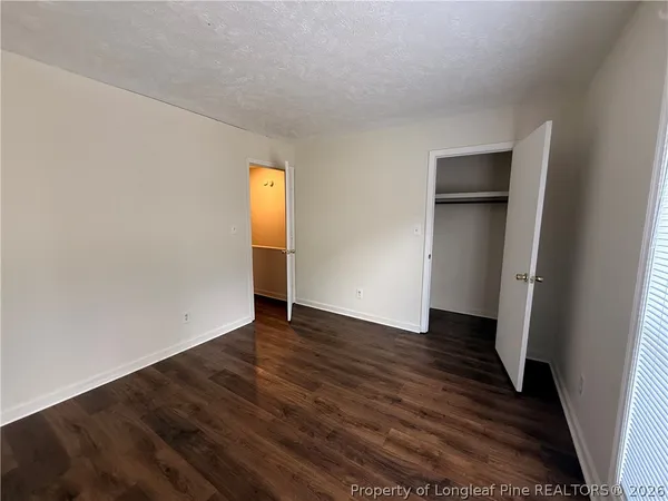 a view of an empty room with wooden floor and closet