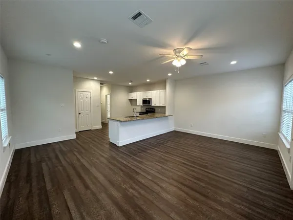a view of kitchen and empty room with wooden floor