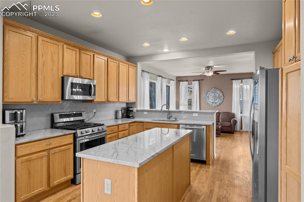 10173 Angeles Road Peyton, CO 80831 - Photo 15 of 50 a kitchen with stainless steel appliances granite countertop a stove a sink dishwasher a microwave oven and a refrigerator with wooden floor