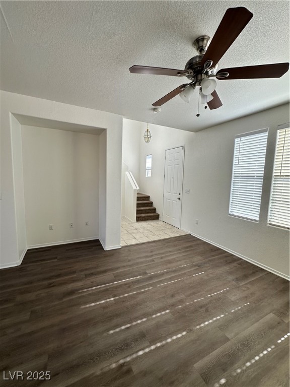 63 Puerto Azul Trail Henderson, NV 89074 - Photo 9 of 26 Unfurnished living room featuring a textured ceiling, healthy amount of natural light, dark wood finished floors, ceiling fan, and stairs