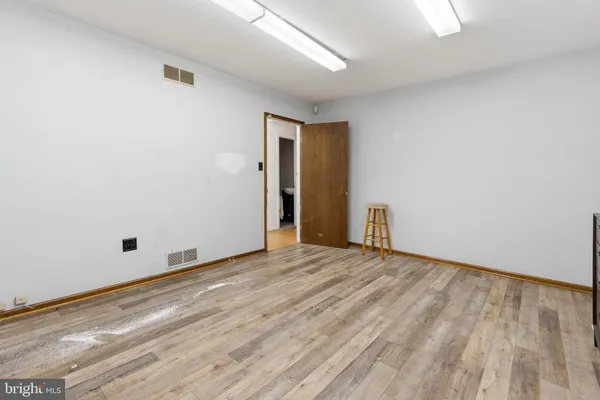 a view of an empty room with wooden floor and fireplace
