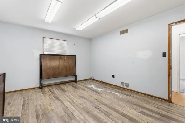 a view of an empty room with cabinet and wooden floor