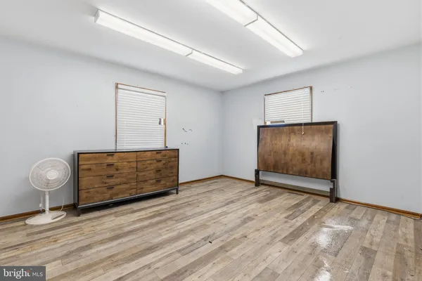 an empty room with wooden floor fireplace and windows