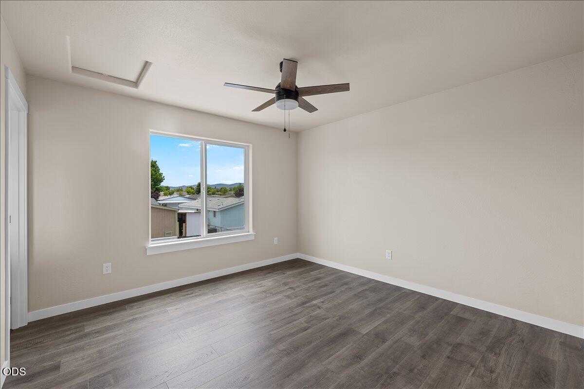 7869 Houston Loop White City, OR 97503 - Photo 11 of 15 an empty room with wooden floor ceiling fan and windows