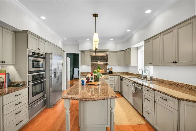 a kitchen with stainless steel appliances kitchen island granite countertop dining table chairs and a view of living room
