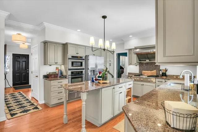 a kitchen with stainless steel appliances kitchen island granite countertop a stove a kitchen island a dining table and chairs