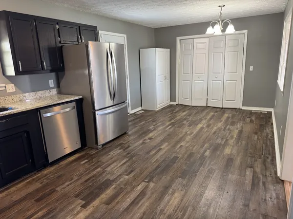 a view of a kitchen with wooden floor refrigerator and cabinet