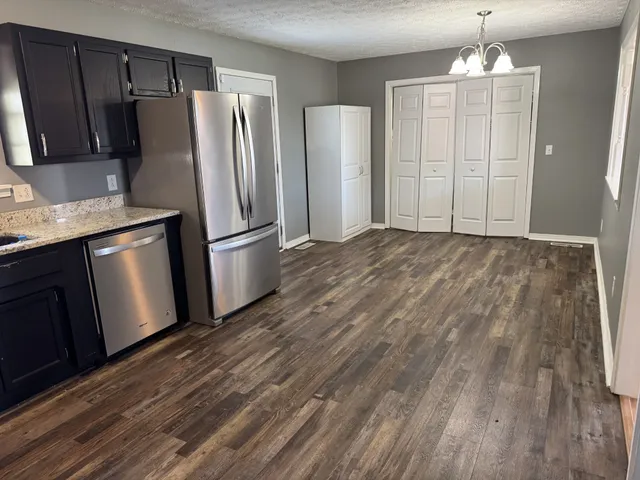 a view of a kitchen with wooden floor refrigerator and cabinet