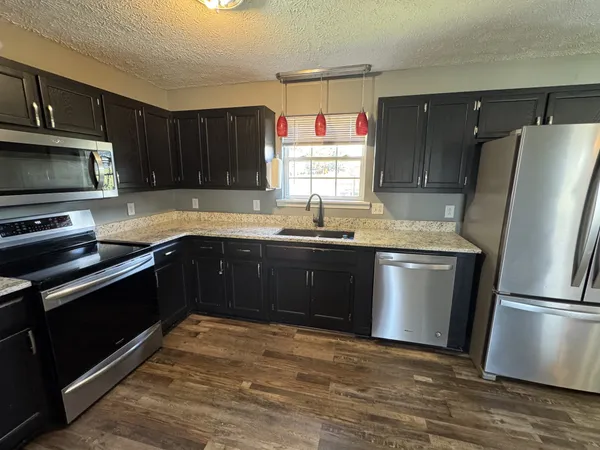 a kitchen with granite countertop a sink stove and microwave