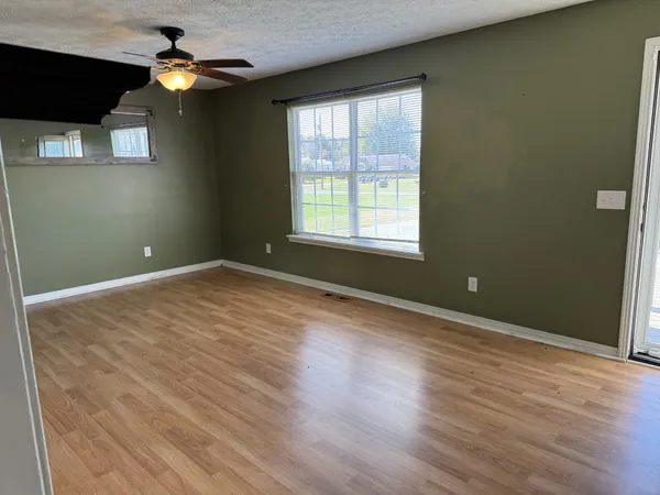 an empty room with wooden floor and windows