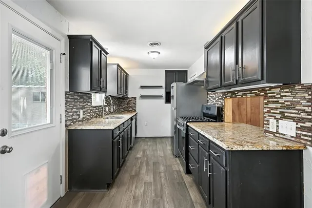 a kitchen with granite countertop stainless steel appliances a sink stove and refrigerator