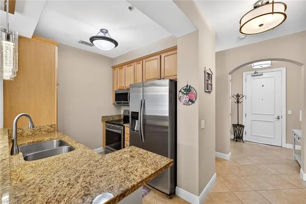 a kitchen with stainless steel appliances granite countertop a refrigerator a stove and a sink