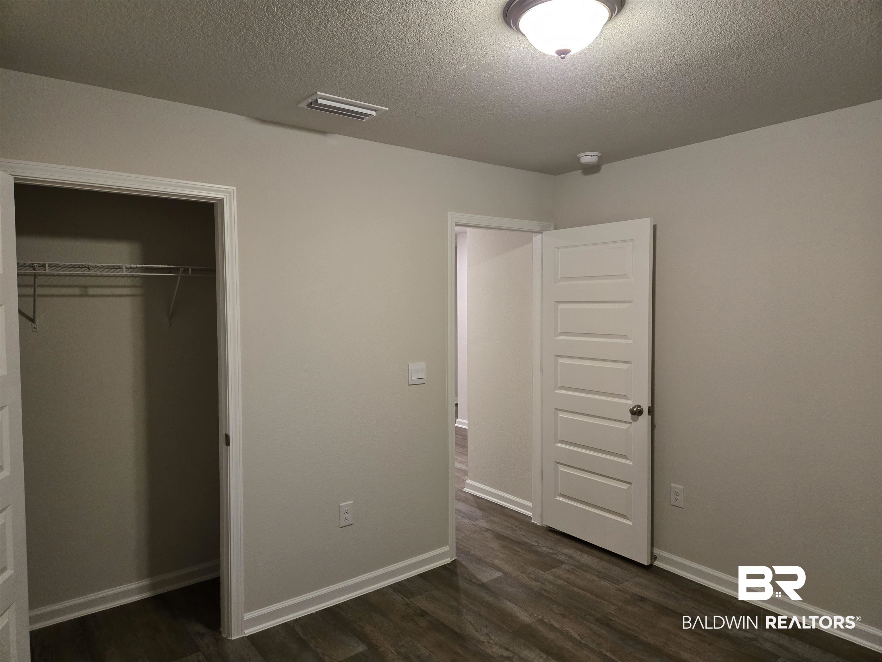 24194 Veranda Circle Elberta, AL 36530 - Photo 8 of 31 Unfurnished bedroom featuring a textured ceiling, dark wood-type flooring, and a closet