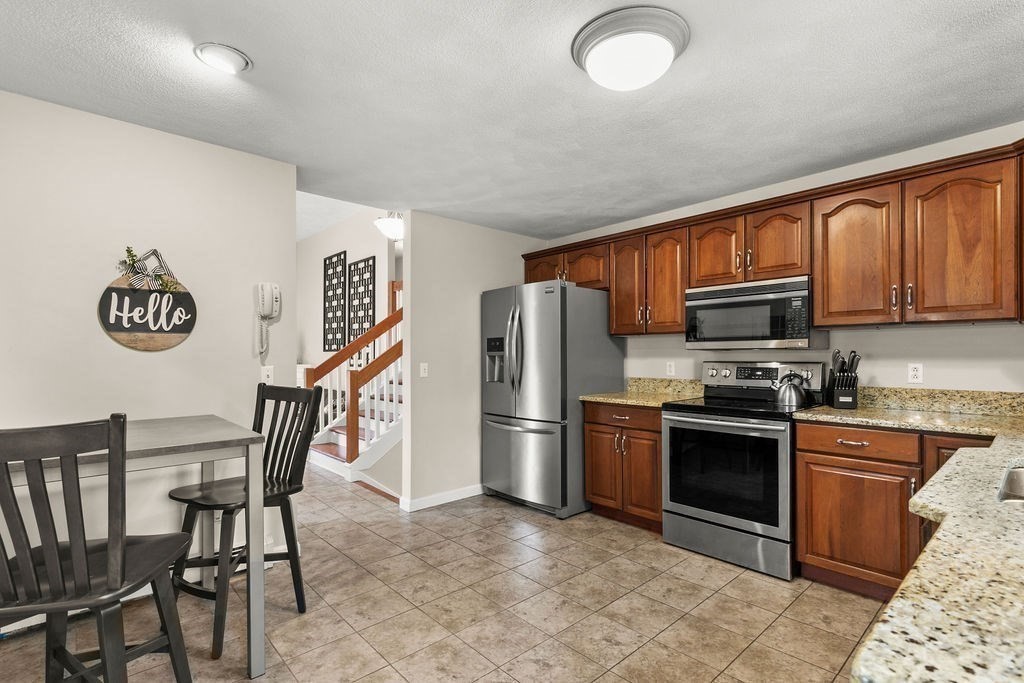 732 Hickory Road North Attleboro, MA 02760 - Photo 6 of 41 a kitchen with stainless steel appliances granite countertop a stove top oven a sink dishwasher a dining table and chairs with wooden floor