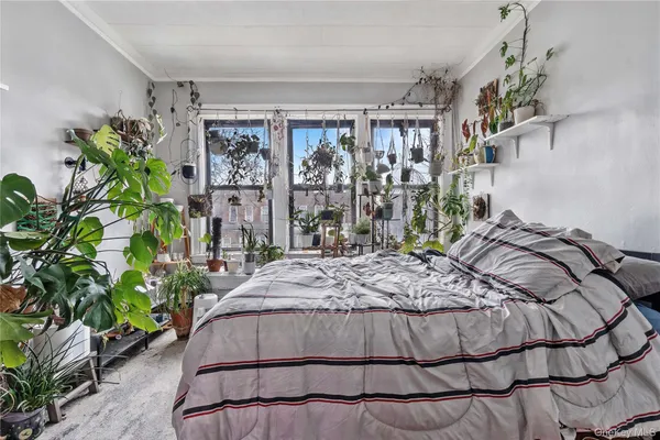 a bed sitting in a bedroom next to a window and a chandelier
