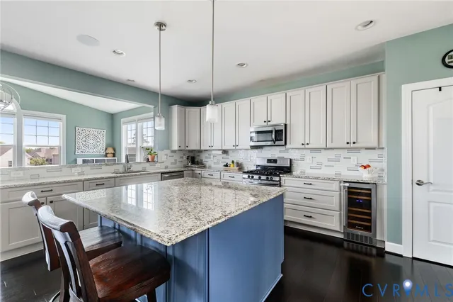 a kitchen with kitchen island granite countertop a stove a sink a dining table and chairs