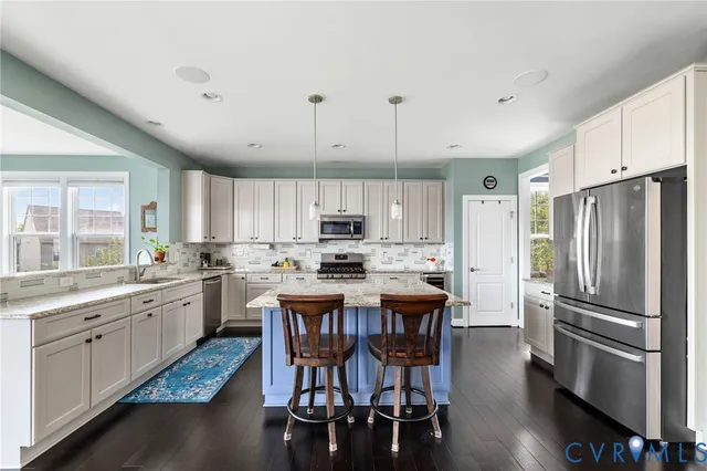 a kitchen with stainless steel appliances kitchen island granite countertop a dining table chairs and granite counter tops
