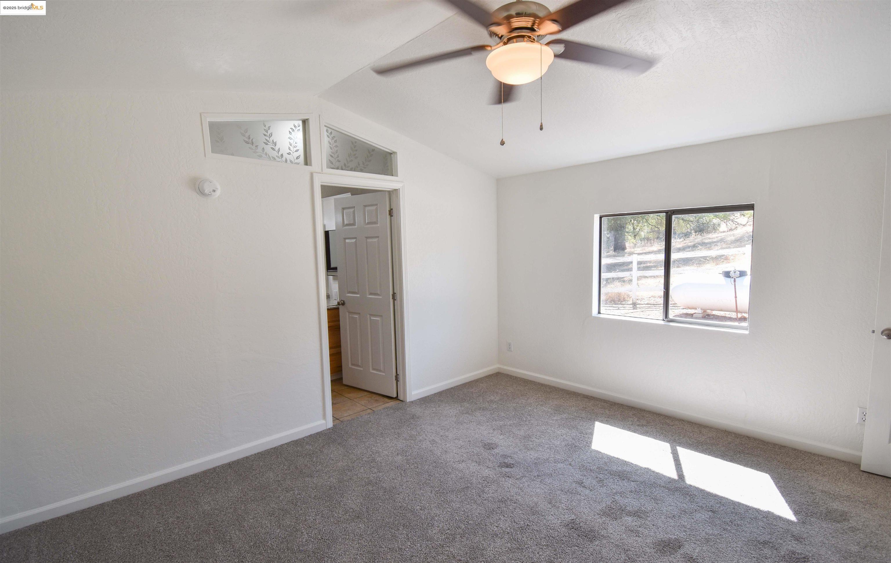 17390 Campbells Flat Road Sonora, CA 95370 - Photo 16 of 37 an empty room with a window and a fan