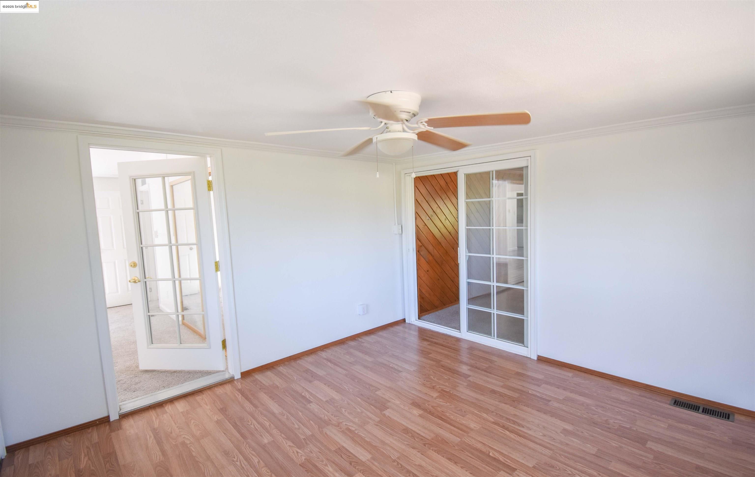 17390 Campbells Flat Road Sonora, CA 95370 - Photo 25 of 37 an empty room with wooden floor ceiling fan and windows