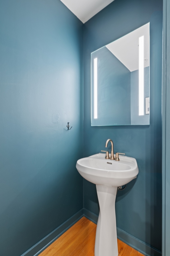 1224 West Van Buren Street, Unit 304 Chicago, IL 60607 - Photo 23 of 28 a bathroom with a sink a mirror and wooden floor