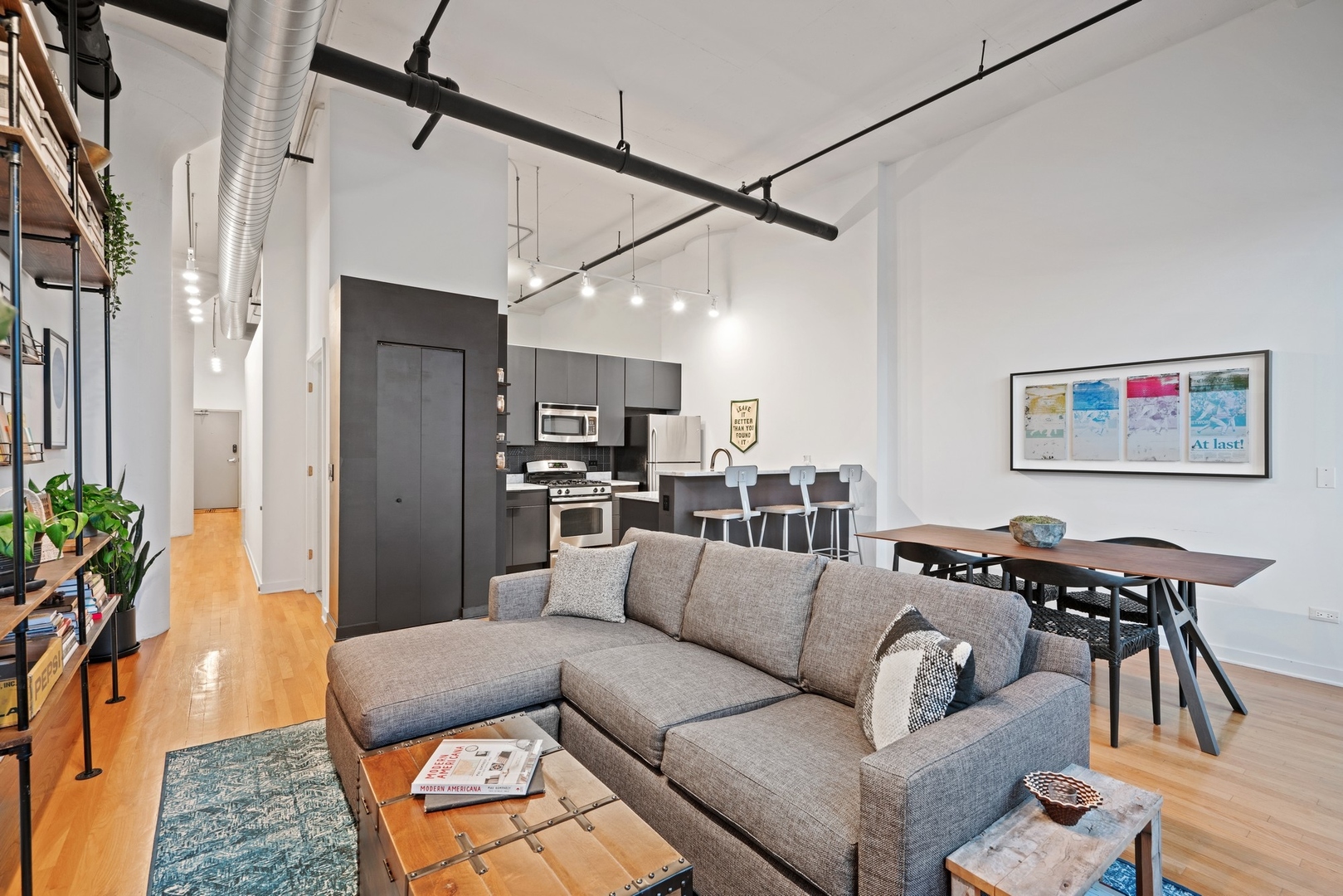 1224 West Van Buren Street, Unit 304 Chicago, IL 60607 - Photo 8 of 28 a living room with furniture and a dining table with wooden floor