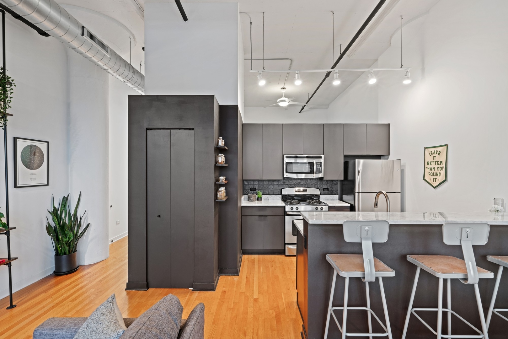 1224 West Van Buren Street, Unit 304 Chicago, IL 60607 - Photo 9 of 28 a kitchen with stainless steel appliances kitchen island granite countertop a refrigerator a stove a sink dishwasher and a dining table with wooden floor