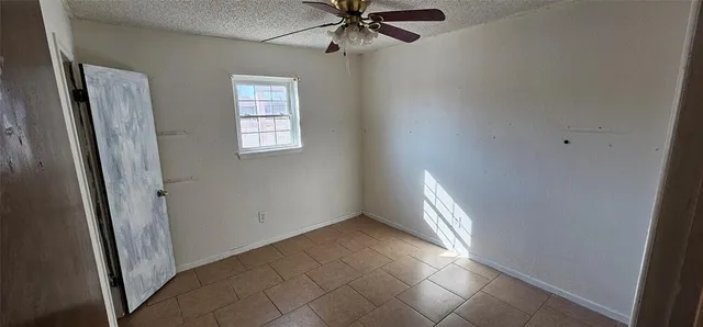 an empty room with windows and fan