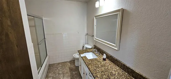 a bathroom with a granite countertop shower and a sink
