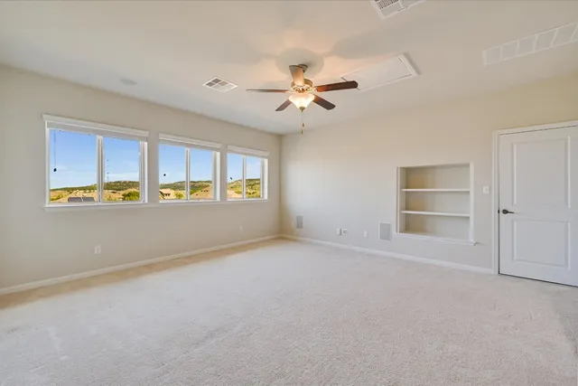 an empty room with windows and fan