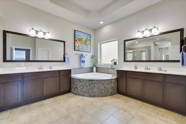 a spacious bathroom with a tub double sink and mirror
